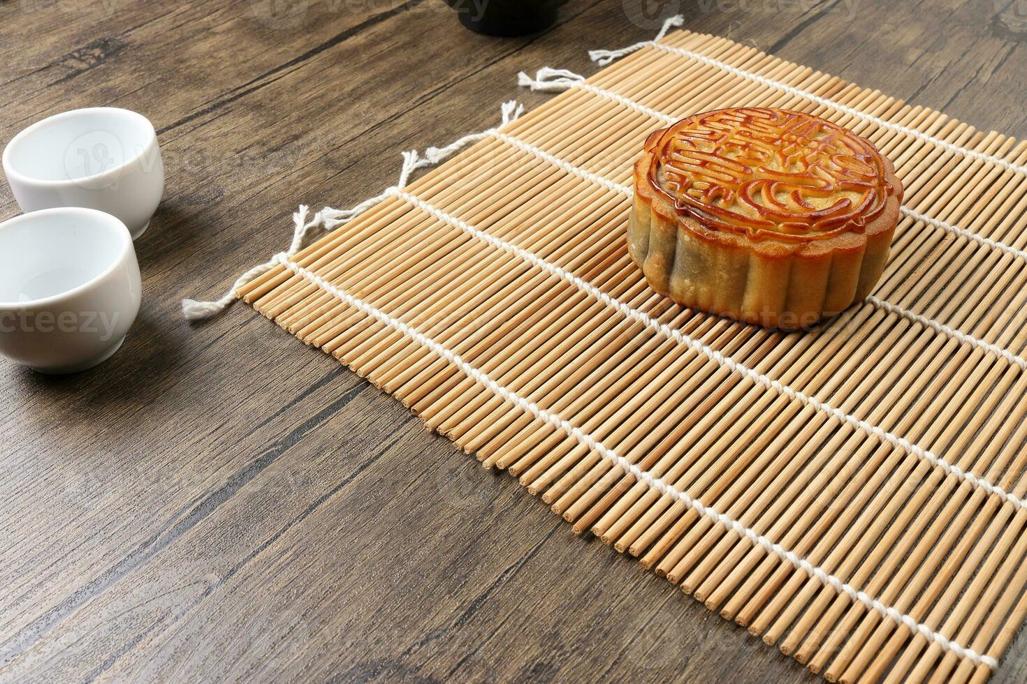 Cinese al forno decorato mooncake medio autunno Festival il giro Luna torta Riempimento regalo desiderio offerta su bambù stuoia al di sopra di di legno tavolo mini tazza foto