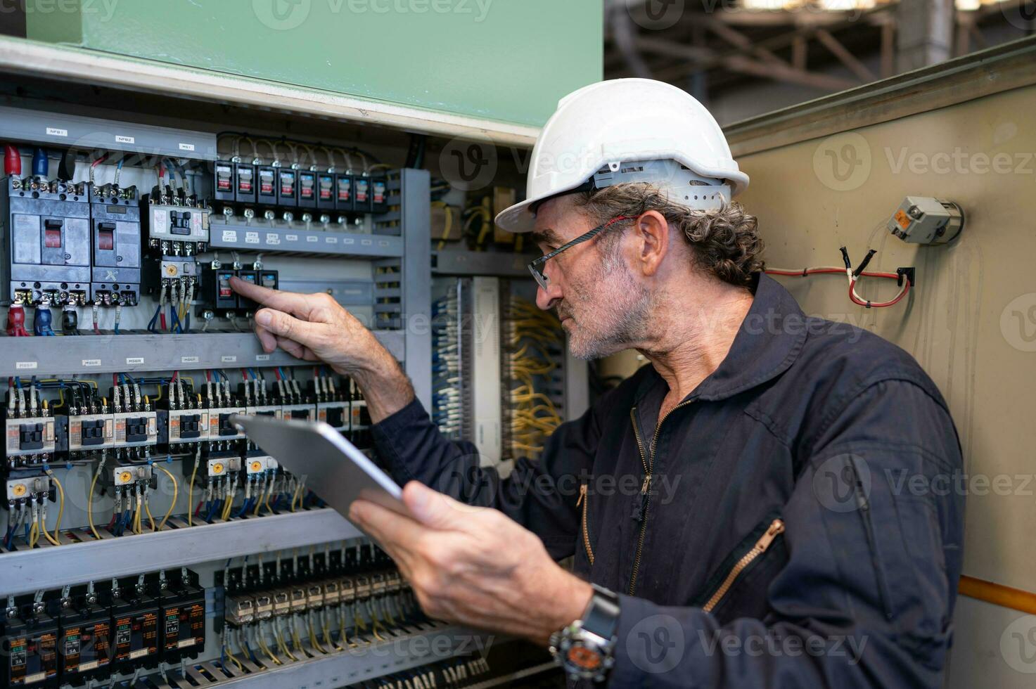 anziano ingegnere ispeziona il elettrico sistema e riparazione il meccanico sistema nel il macchina controllo mobiletto. nel ordine per il macchina per ritorno per normale operazione foto