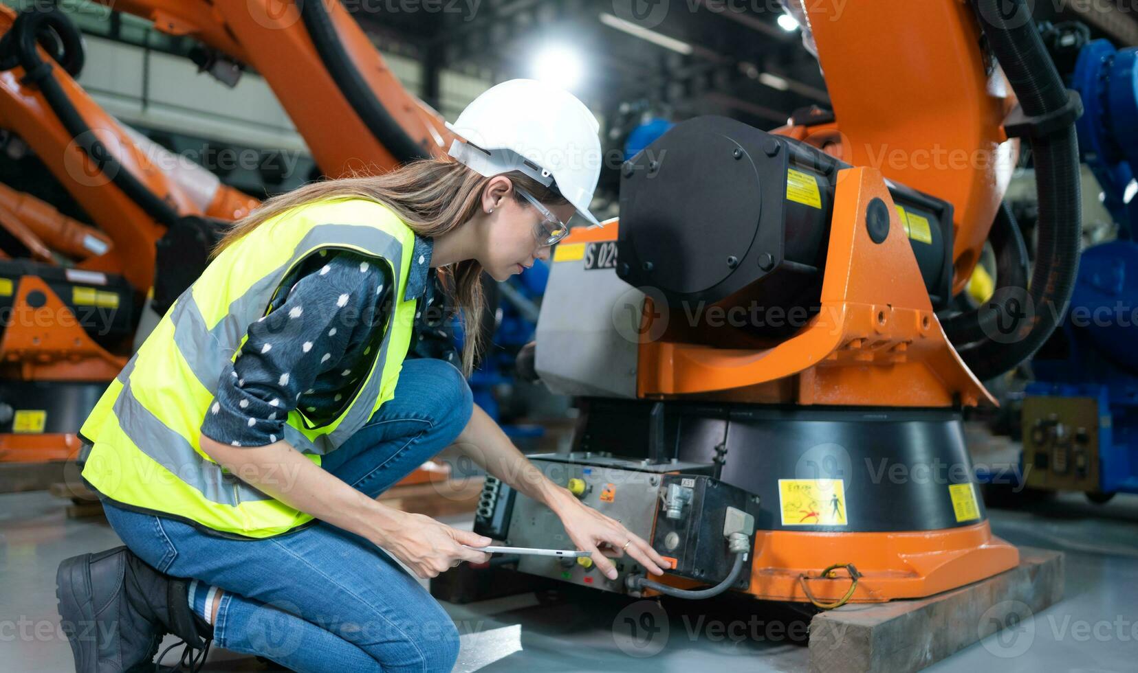 femmina tecnico ispezionando e riparazione robotica braccio nel robot hangar e test il operazione di il macchina dopo essere Usato per un' mentre, come bene come in aggiornamento il Software e calibrazione foto