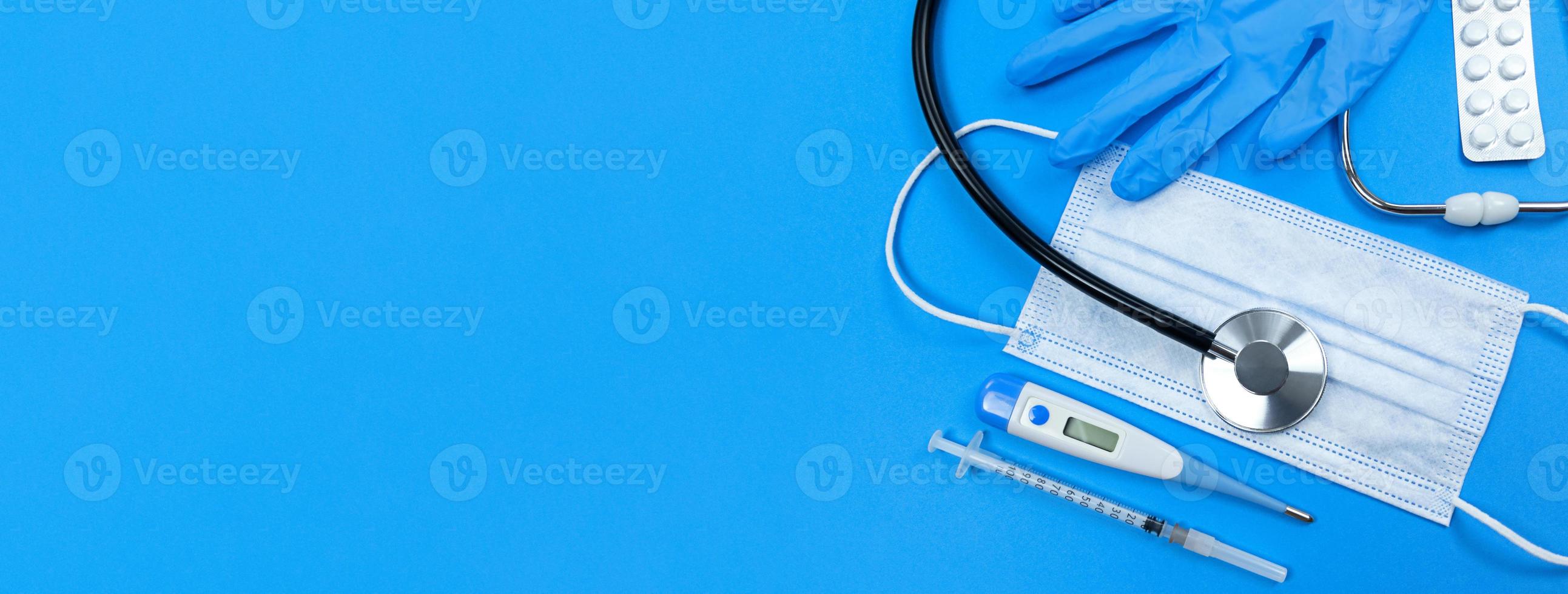 stetoscopio maschera facciale siringa medica termometro pillole blister e guanti medici su sfondo blu piatto banner laici con spazio di copia foto