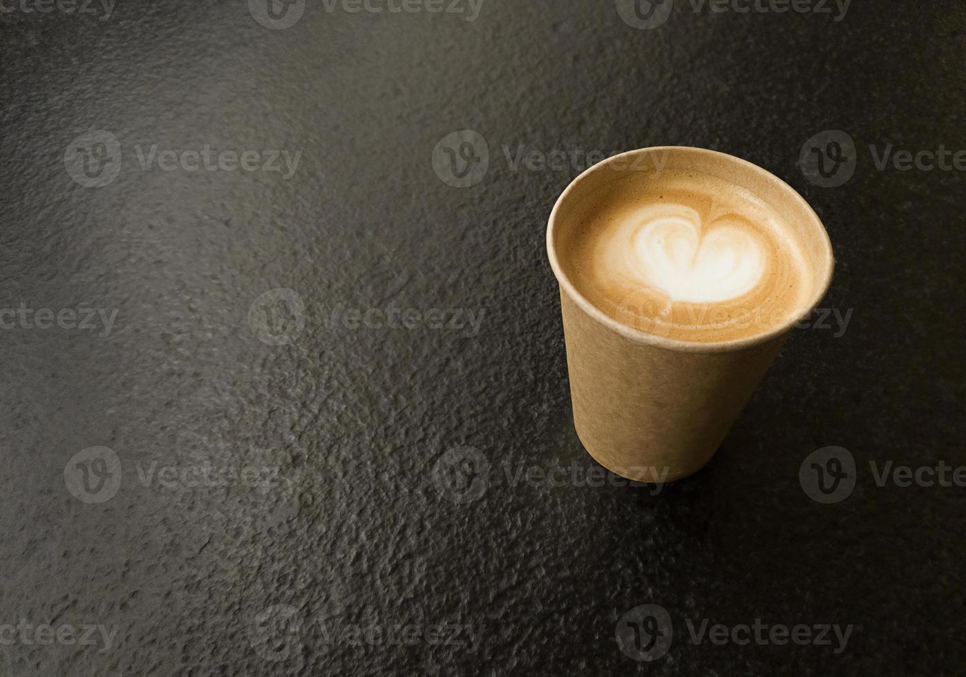 tazza di caffè artigianale con spazio copia a forma di cuore su un tavolo strutturato nero foto