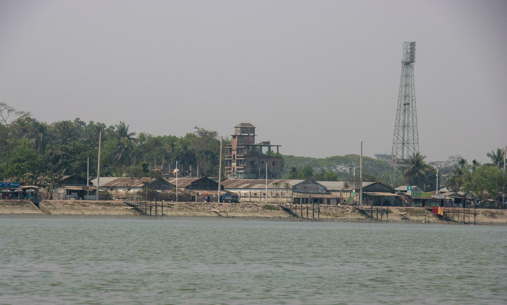 industriale Riva del fiume con fabbriche e elettrico polo. Riva del fiume pieno di calcestruzzo pilastri. bellissimo sud-est asiatico fiume e blu cielo sparo. costa di un' fiume e industriale la zona. panoramico fiume Visualizza. foto