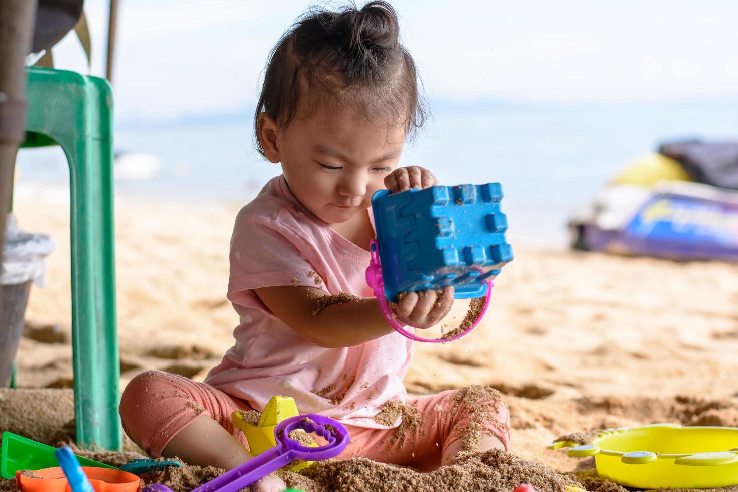 carina bambina asiatica che gioca con i giocattoli da spiaggia sulla spiaggia foto