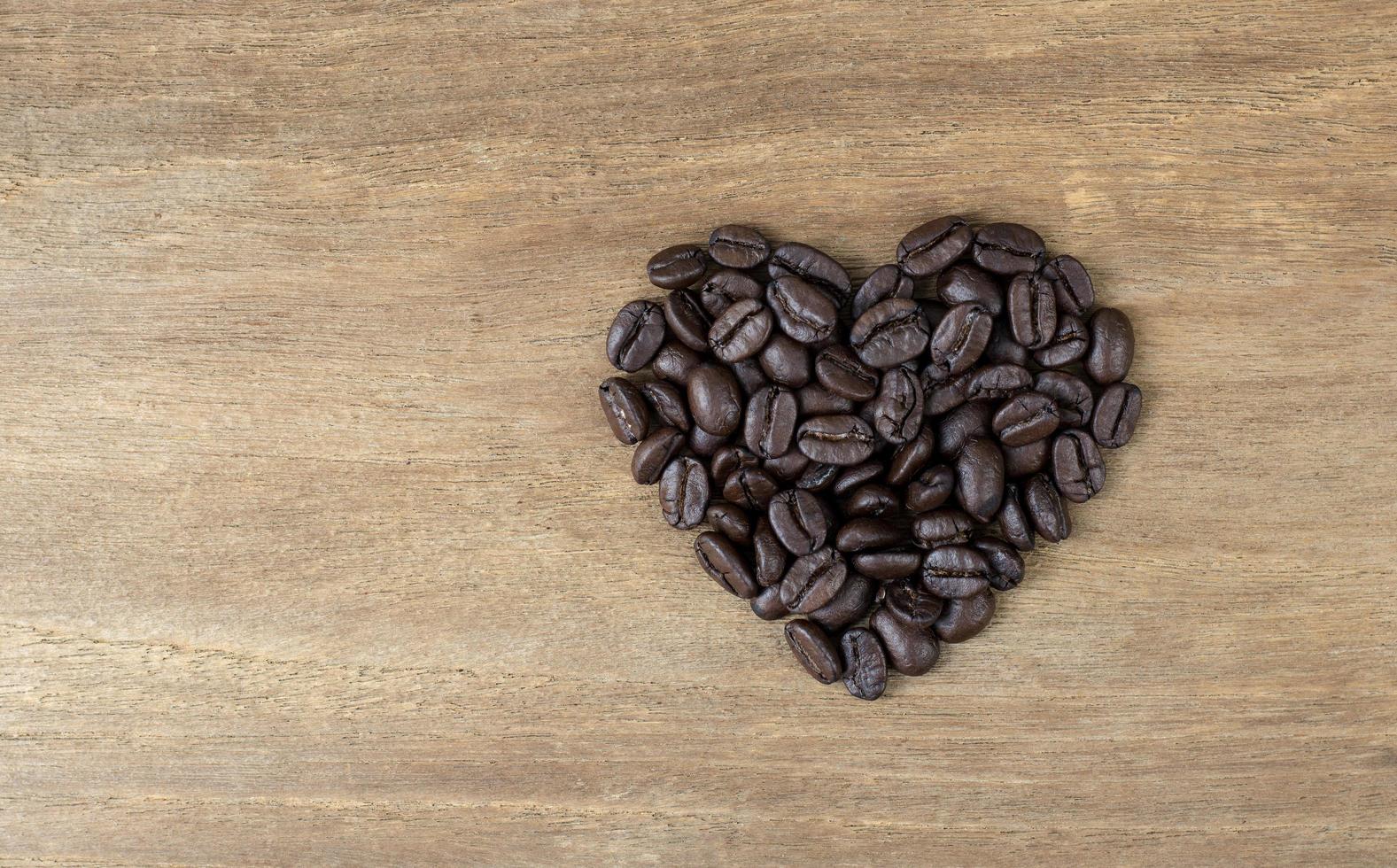 chicchi di caffè a forma di cuore su fondo in legno foto