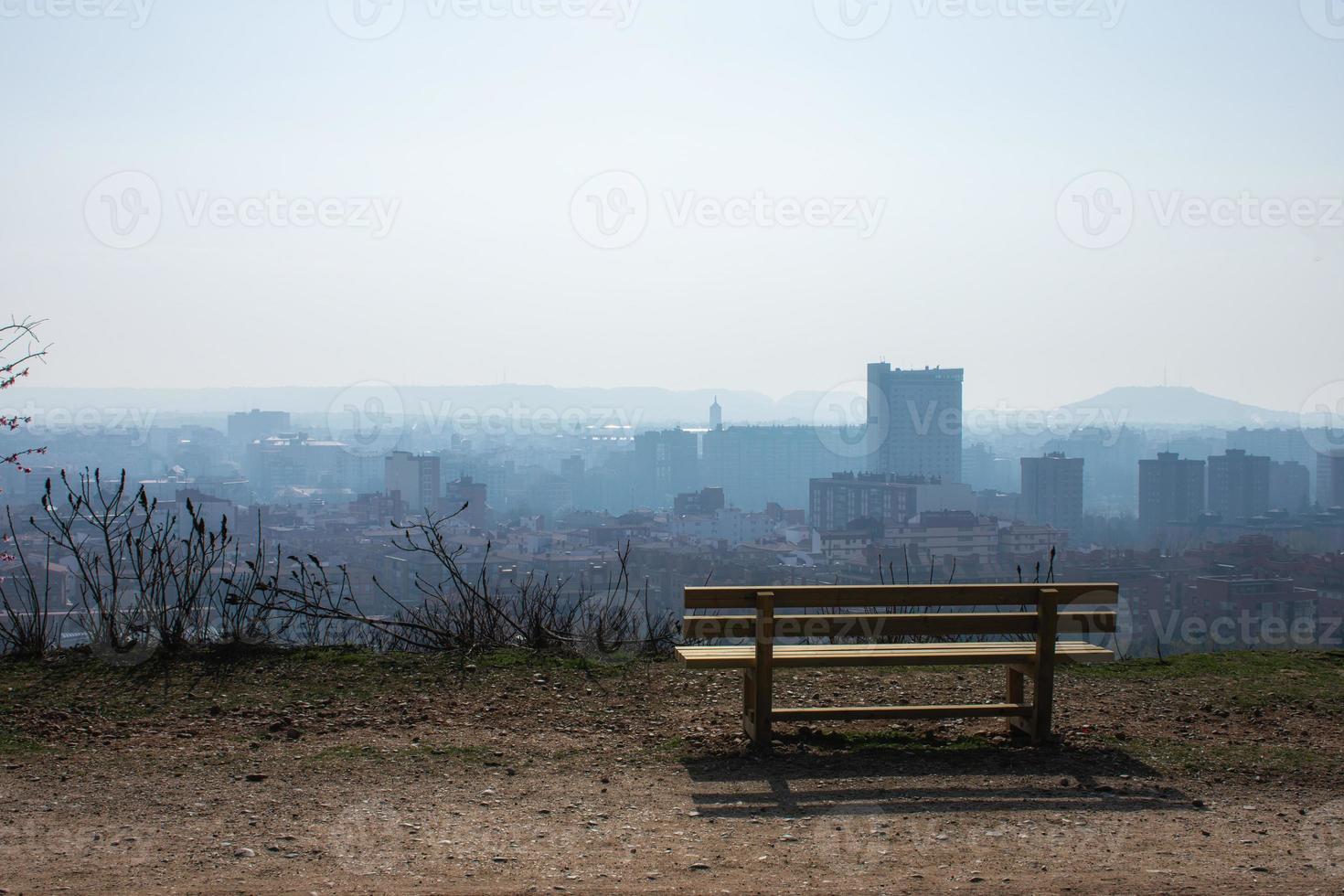 panca in legno vuota nel parco di primavera sopra la città foto