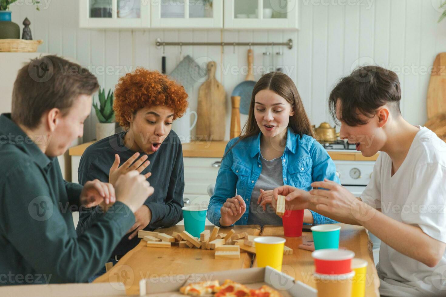 casa festa. amici la spesa tempo insieme giocando nel tavola gioco schianto di legno Torre a casa. contento diverso gruppo avendo divertimento insieme interno. misto gara giovane amici migliore amici godendo fine settimana. foto