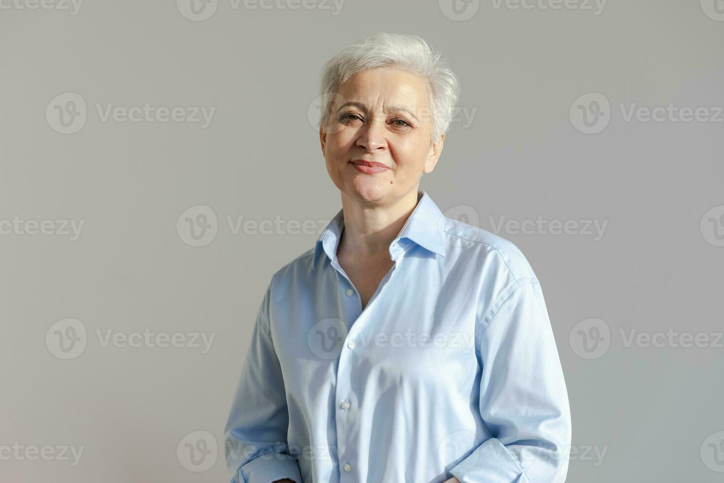 fiducioso elegante europeo mezzo anziano anziano donna. più vecchio maturo 60s signora sorridente nel bianca sfondo. contento attraente anziano femmina guardare telecamera vicino su viso colpo alla testa ritratto. contento le persone. foto