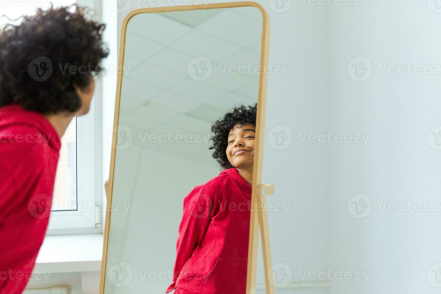 amore te stesso. bellissimo giovane sorridente africano americano donna danza godendo sua specchio riflessione. nero signora guardare a specchio guardare fiducioso e contento. se stesso amore concetto. foto