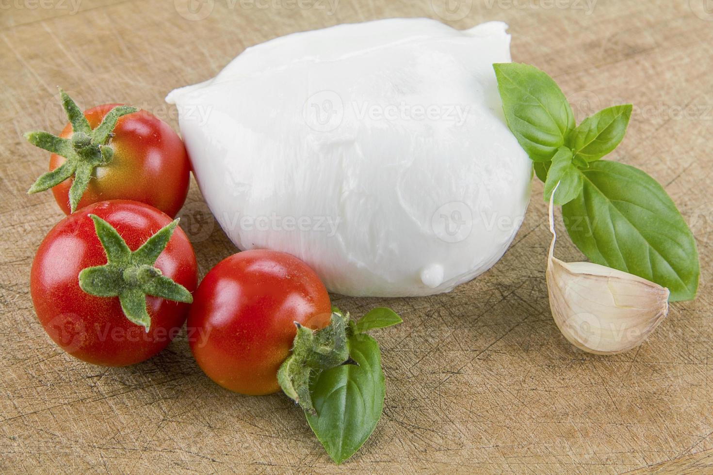 mozzarella biologica italiana con pomodorini e basilico su un tagliere foto