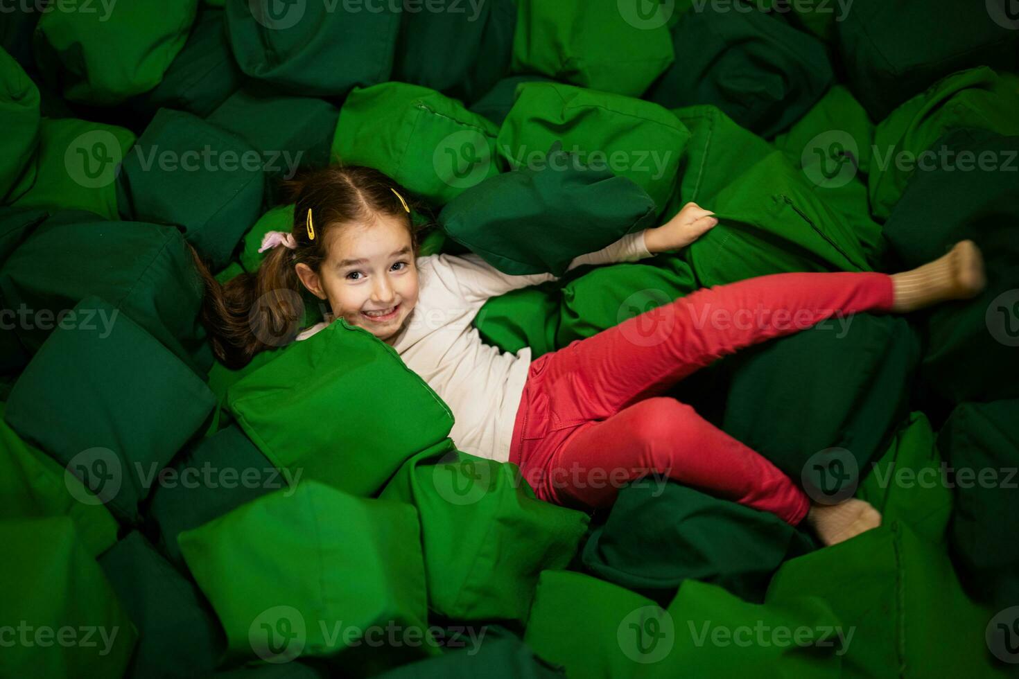 poco ragazza ragazzo bugie su verde morbido cubi a terreno di gioco parco. bambino nel attivo divertimenti. foto