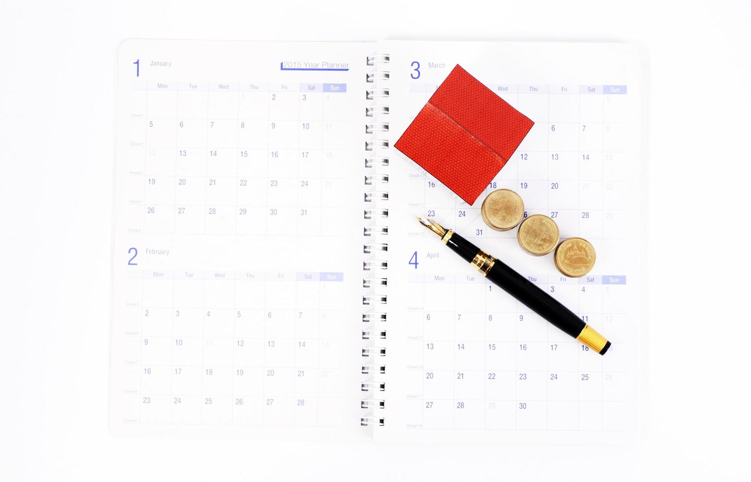 penna stilografica e monete e casa di carta sulle pagine del libro del calendario per il concetto di pianificazione del mutuo ipotecario foto