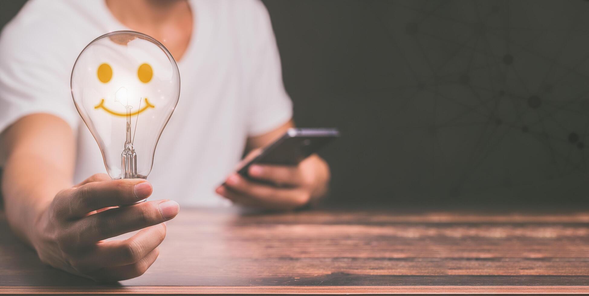 mano di un uomo con una lampadina e c'è un'icona a forma di ingranaggio foto