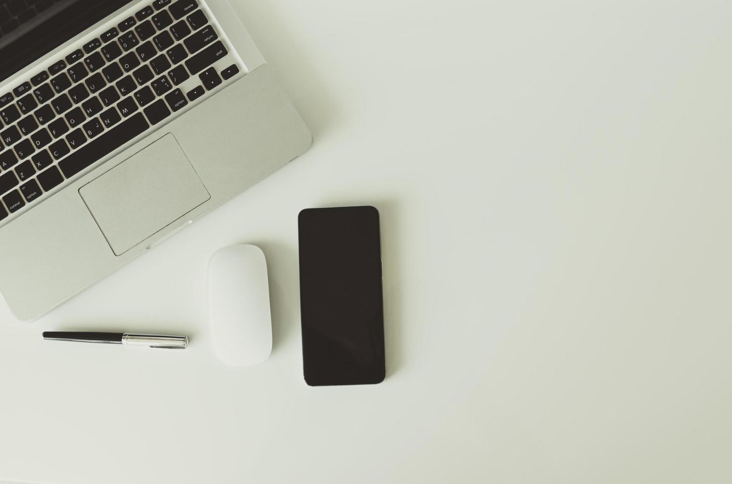 computer portatile, mouse, penna e smartphone su uno sfondo bianco foto