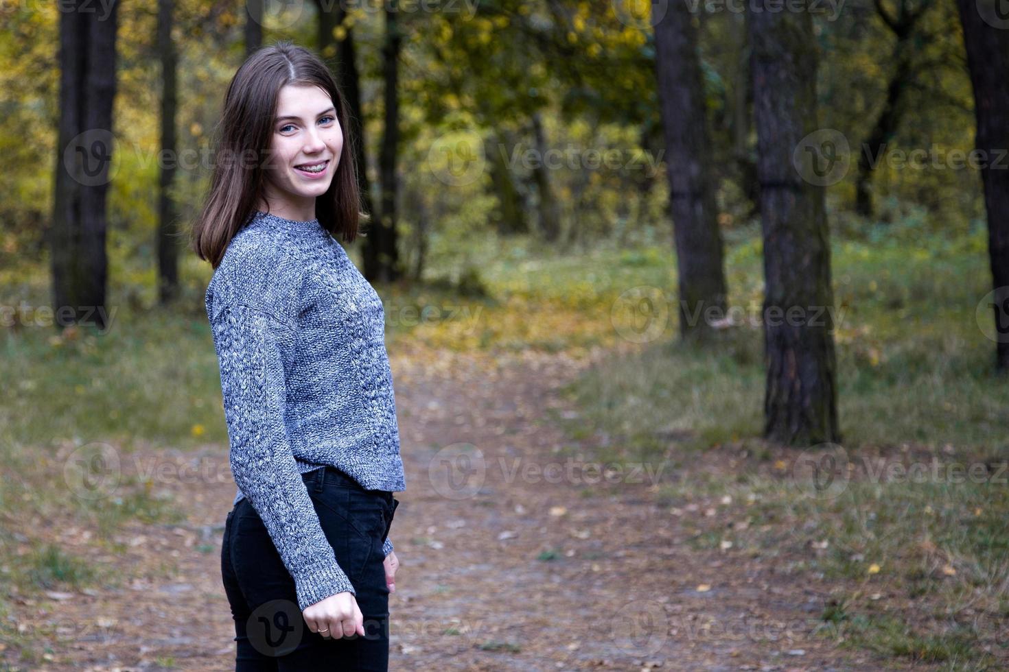 ragazza carina in un maglione grigio nella foresta di autunno foto