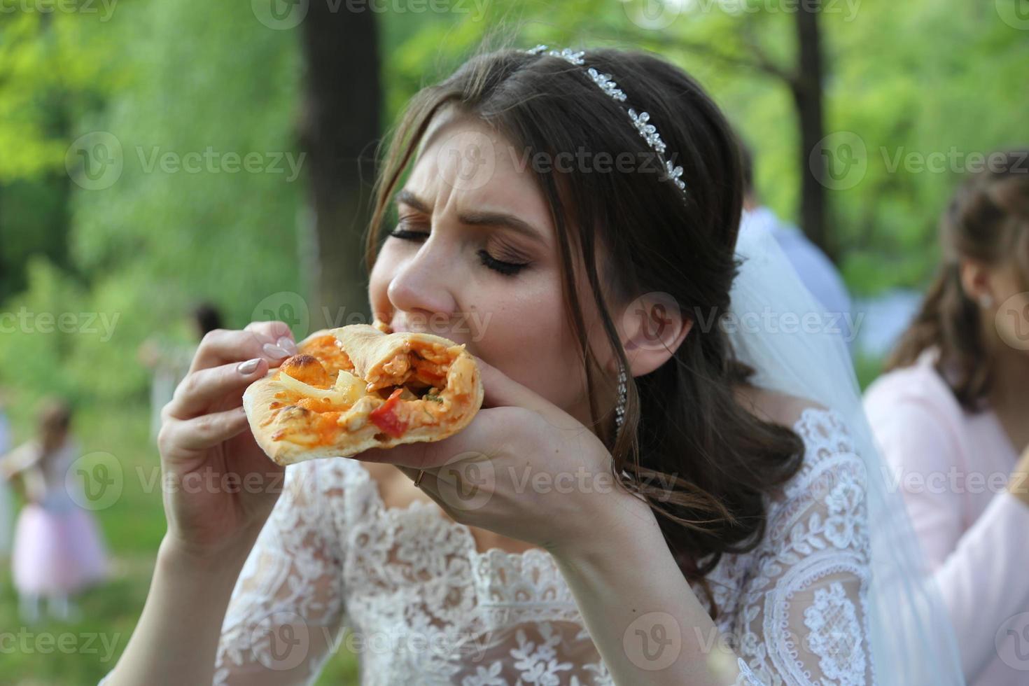 sposa mangia pizza all'aperto nella foresta foto