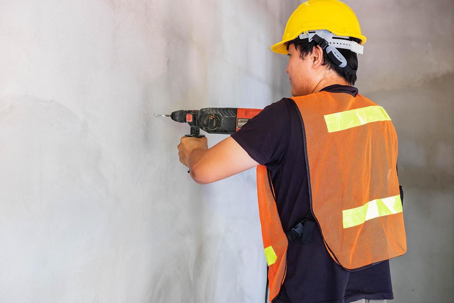 il meccanico sta perforando il muro di cemento foto