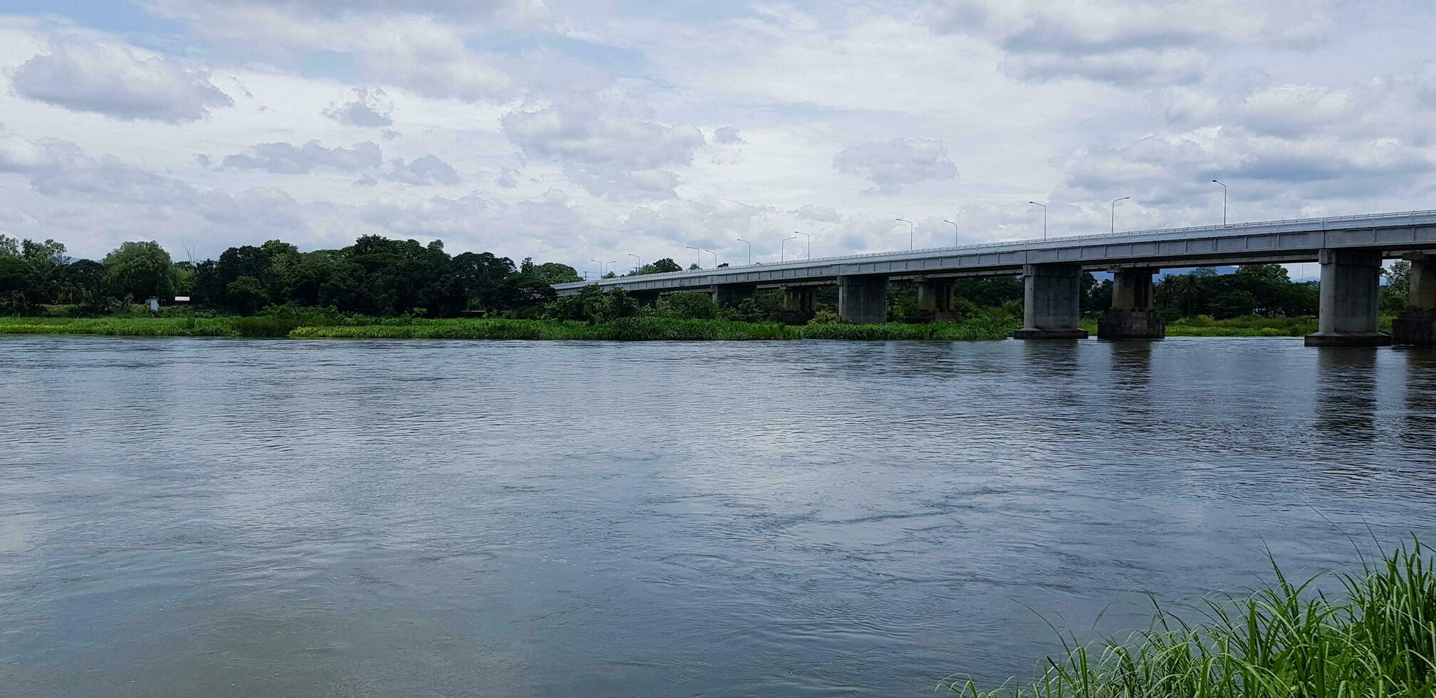 bellissimo fiume Visualizza e albero con un' calcestruzzo ponte attraverso il fiume o lago. costruzione, mezzi di trasporto e natura. foto