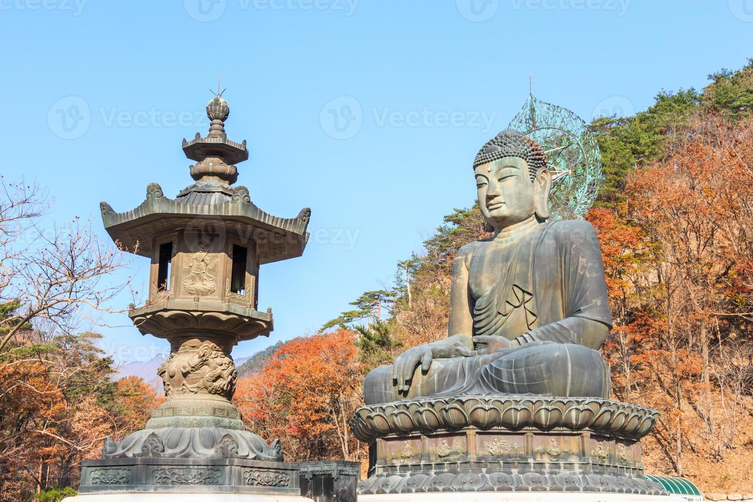 La tradizionale statua del Buddha e alberi colorati al tempio Shinheungsa nel Parco Nazionale di Seoraksan in autunno Corea del Sud foto