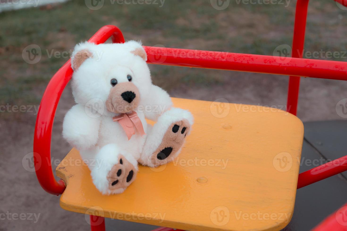 primo piano di un orsacchiotto seduto su un'altalena per bambini foto