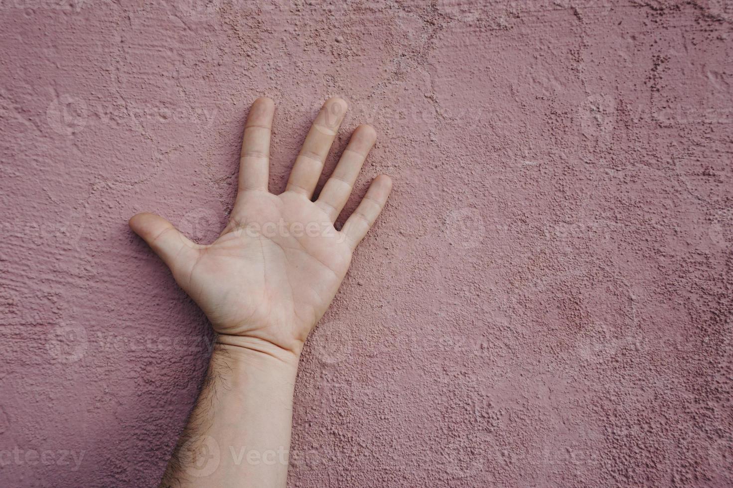 gesticolando con la mano sul muro rosa foto