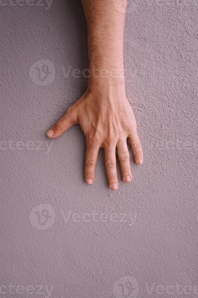 gesticolando con la mano sul muro rosa foto