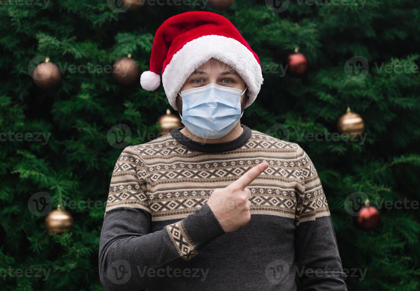 Close-up ritratto di uomo che indossa un cappello di Babbo Natale e mascherina medica foto