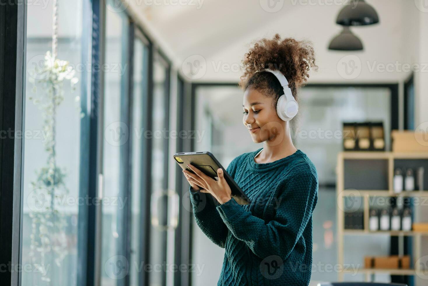 giovane africano donna ascoltando musica a partire dal cuffie e scrittura Nota per sua opera idea nel diario libro.lei nel casa ufficio foto