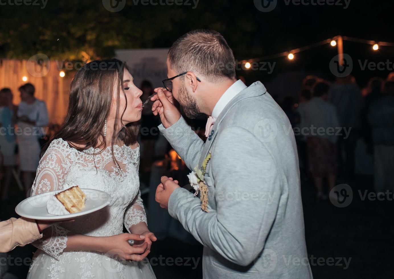 gli sposi alla festa tagliano e provano la torta nuziale foto