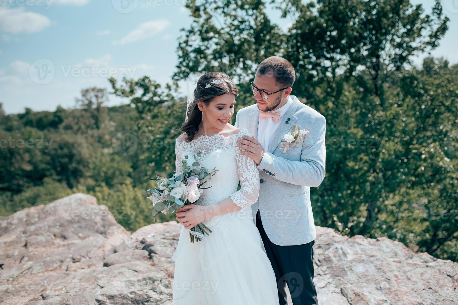 foto di matrimonio della sposa e dello sposo in un colore rosa grigio sulla natura nella foresta e nelle rocce