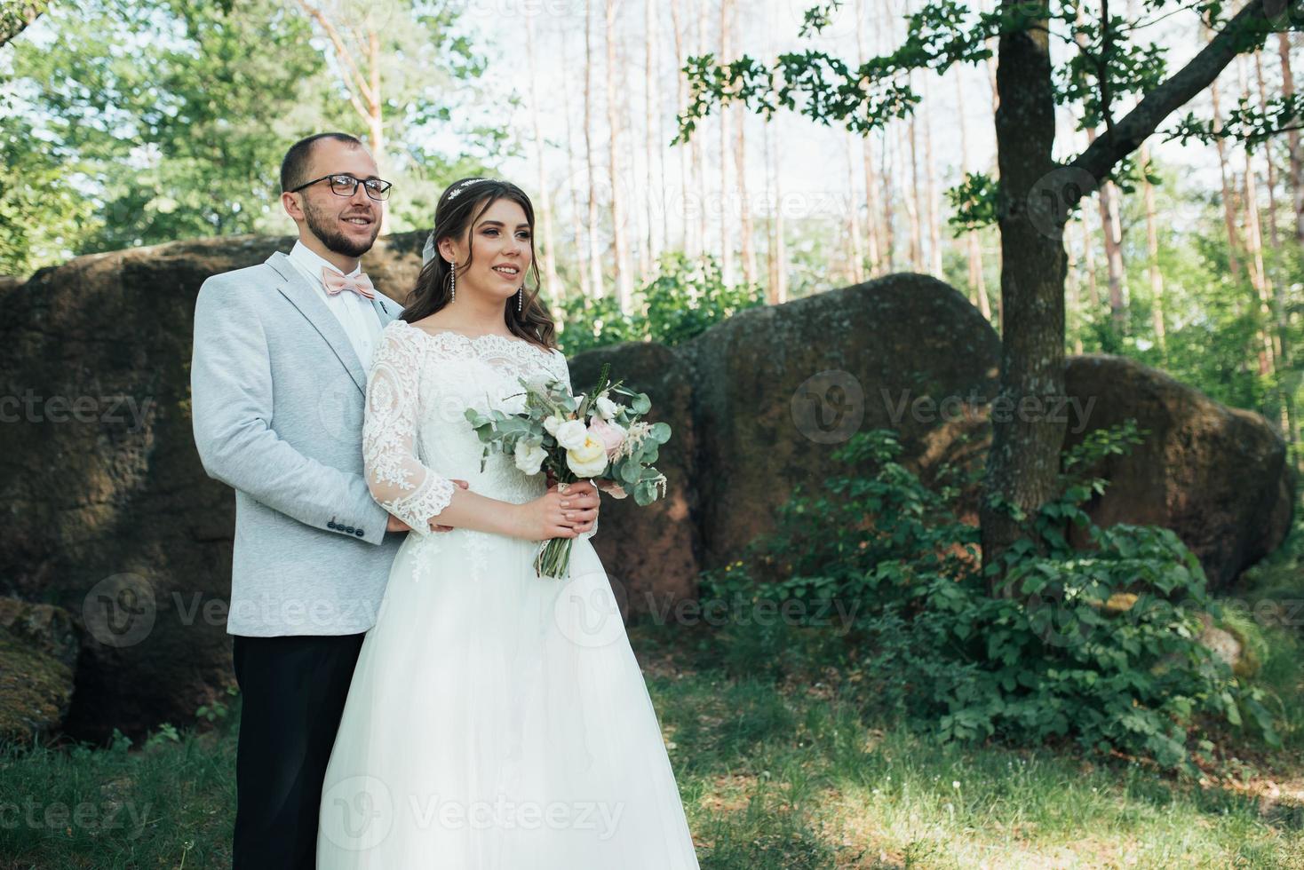 foto di matrimonio della sposa e dello sposo in un colore grigio rosa sulla natura nella foresta e nelle rocce