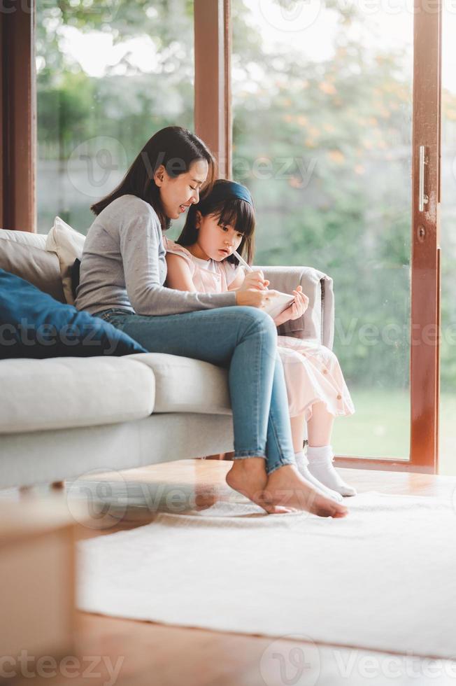 madre e figlia utilizzando la tavoletta digitale per studiare insieme foto