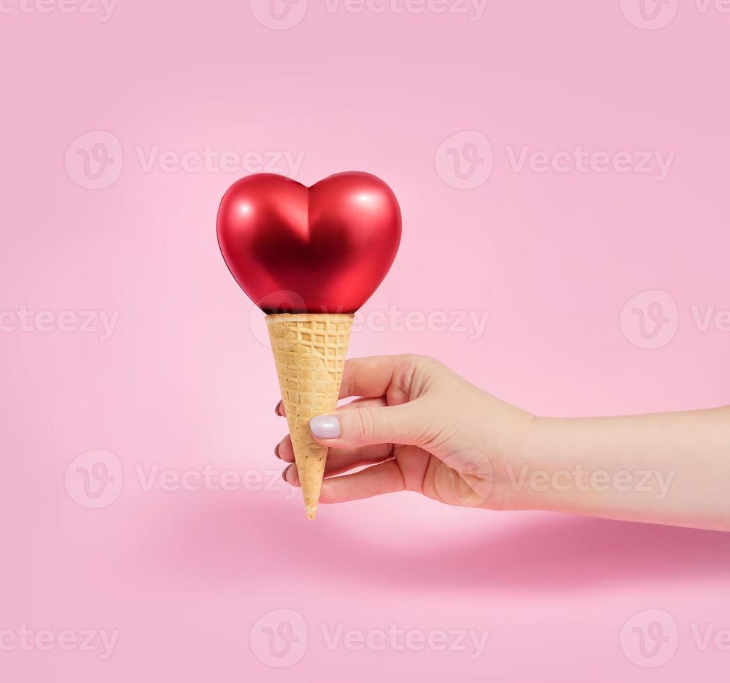 una mano femminile tiene un cono di cialda con un cuore foto