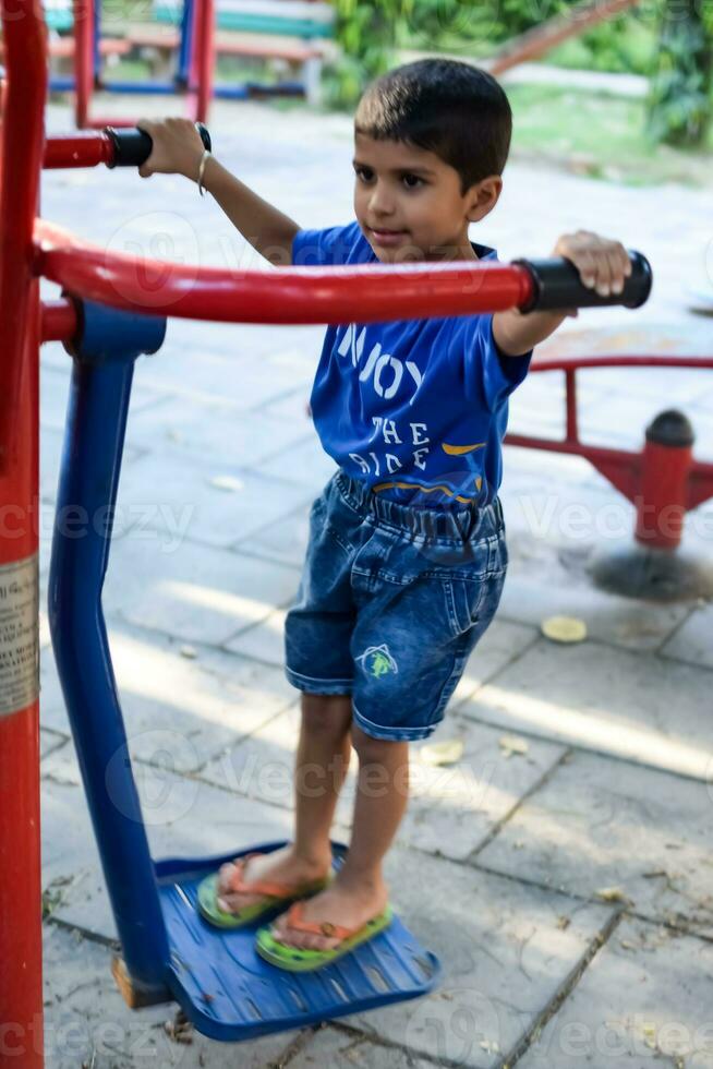 asiatico ragazzo fare routine esercizio nel società parco durante il mattina volta. carino poco ragazzo esercizio e Palestra per mantenere lui stesso in forma per vita. del bambino esercizio all'aperto sparare foto