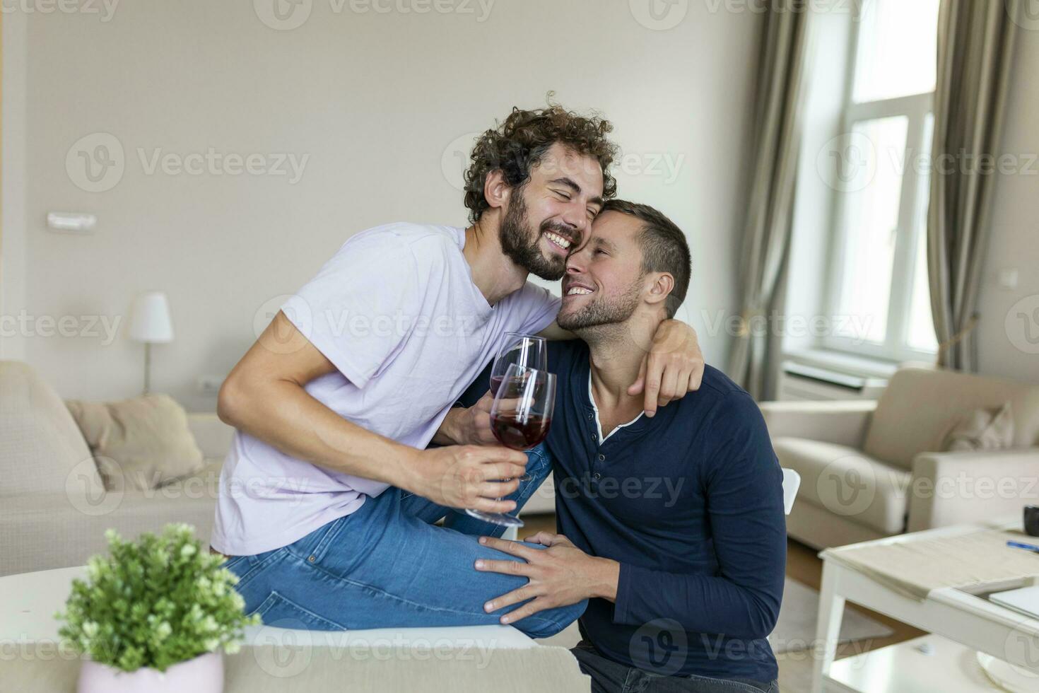 LGBTQ coppia Abbracciare una persona ogni altro e strizzando vino al chiuso. Due romantico giovane maschio Gli amanti guardare a ogni altro mentre seduta insieme nel loro vivente camera. giovane gay coppia essere romantico a casa. foto