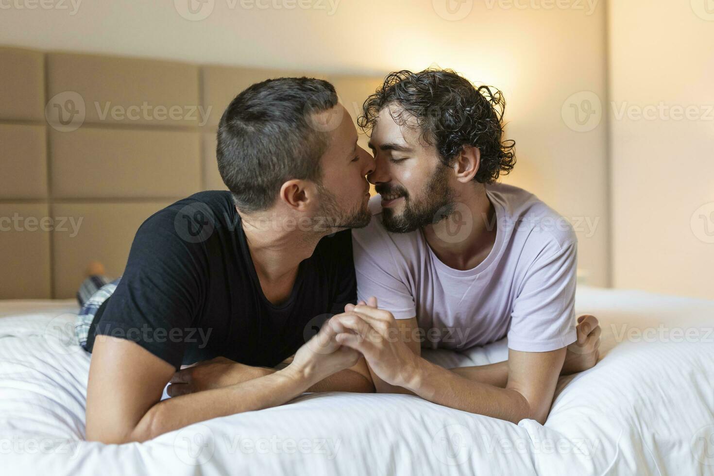 contento gay coppia dire bugie giù su il letto a casa, abbracciare e flirtare. lgbt gay coppia amore momenti felicità concetto foto