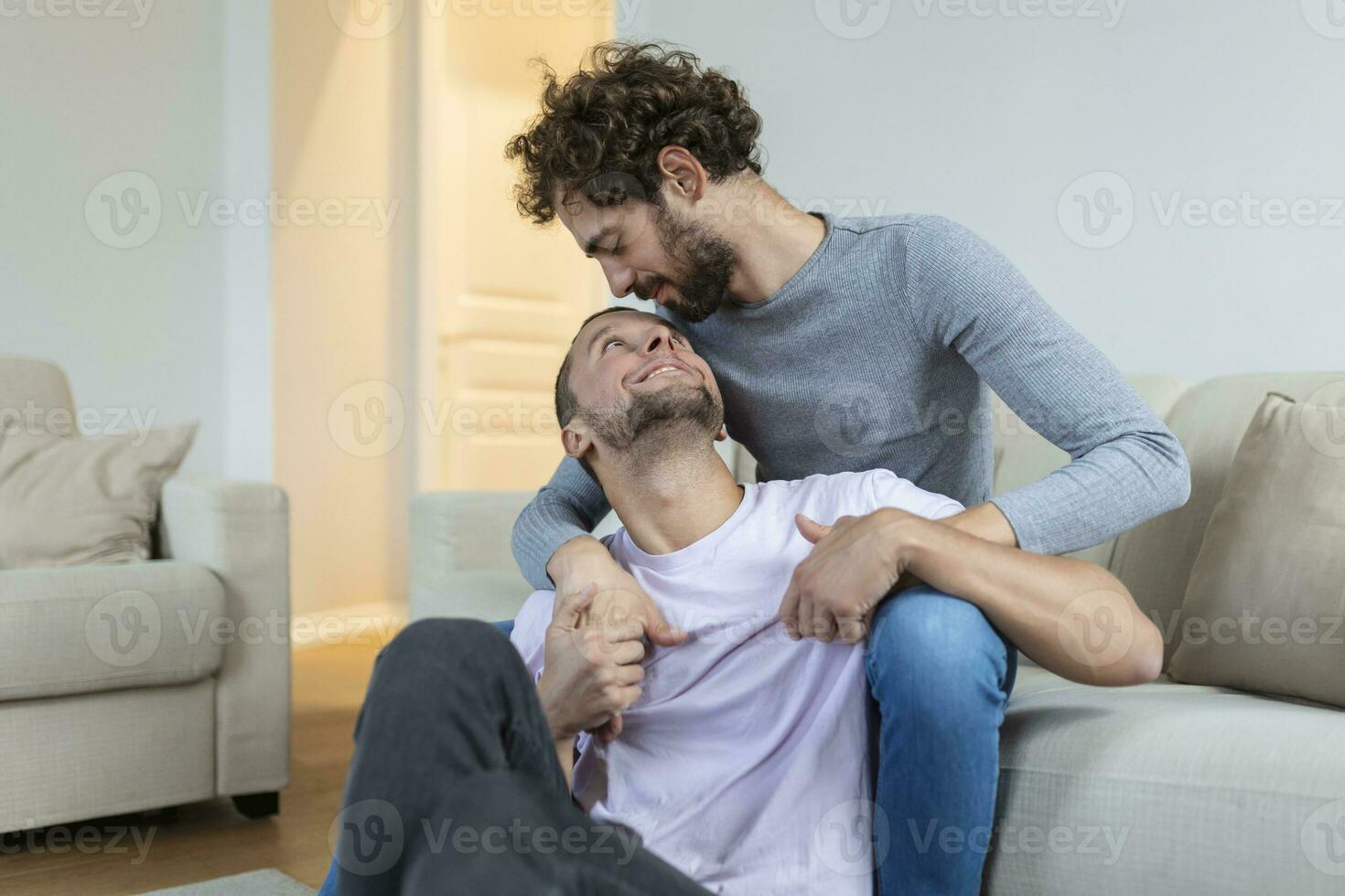 amorevole stesso sesso maschio gay coppia dire bugie su divano a casa e rilassante, coccole insieme foto