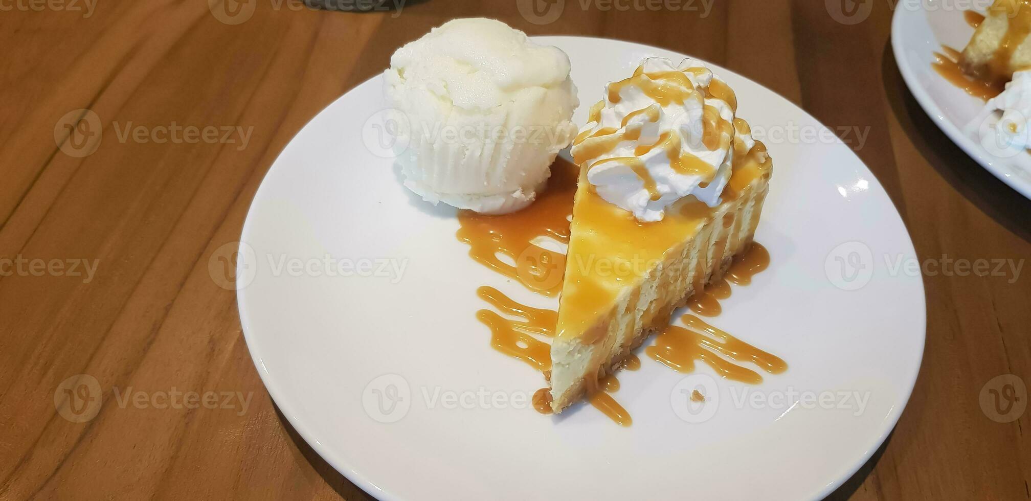 un' fetta di caramello formaggio torta con caramello sciroppo su superiore e frustato crema e vaniglia ghiaccio crema servito nel bianca piatto foto