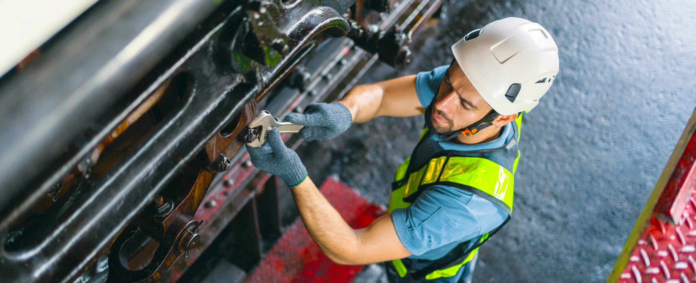 lavoratore uomo controllo e utilizzando chiave inglese per Manutenzione metallo macchina a fabbrica foto