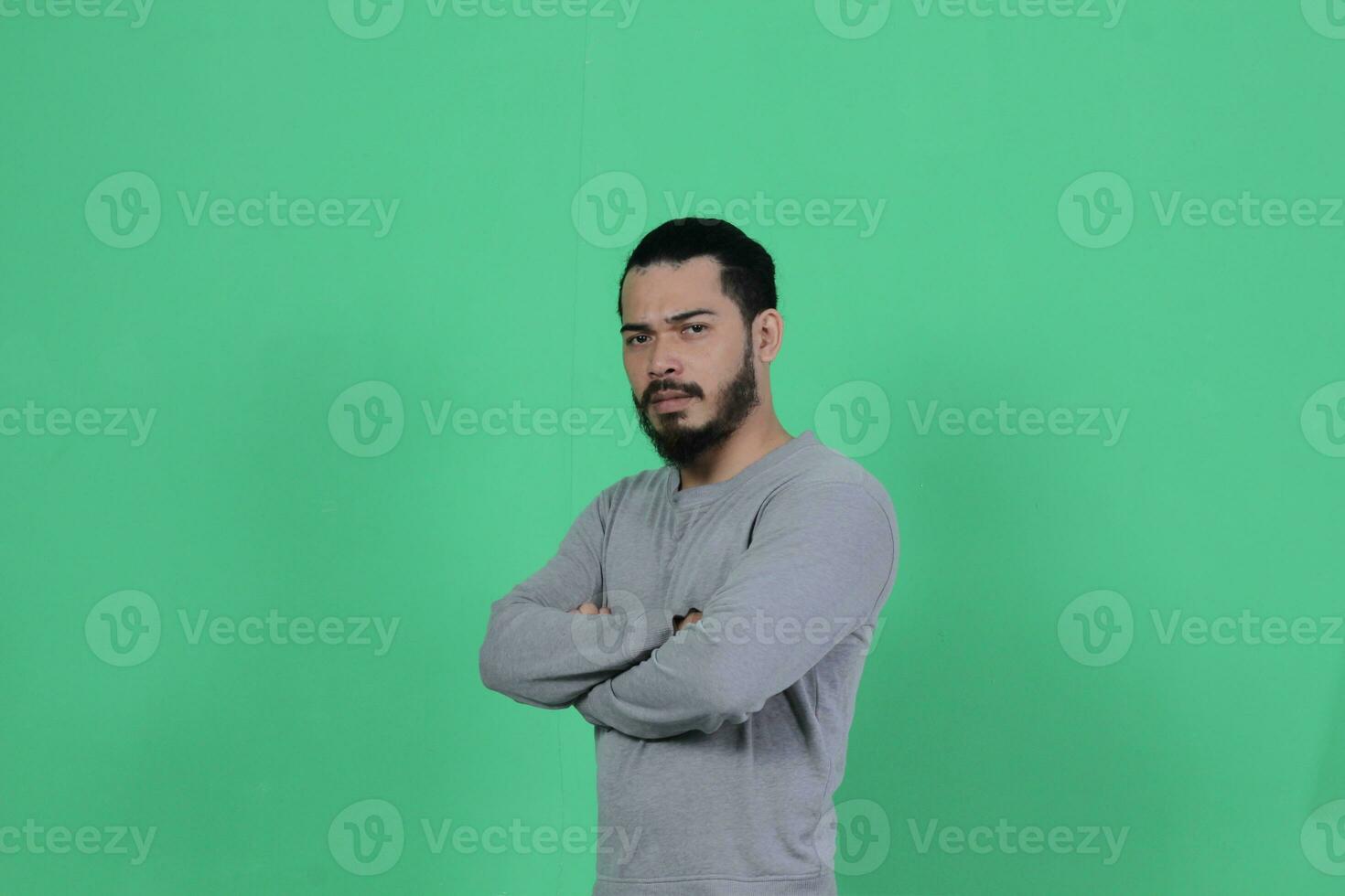 barbuto asiatico uomo pose indossare un' grigio camicia contro un' verde sfondo foto