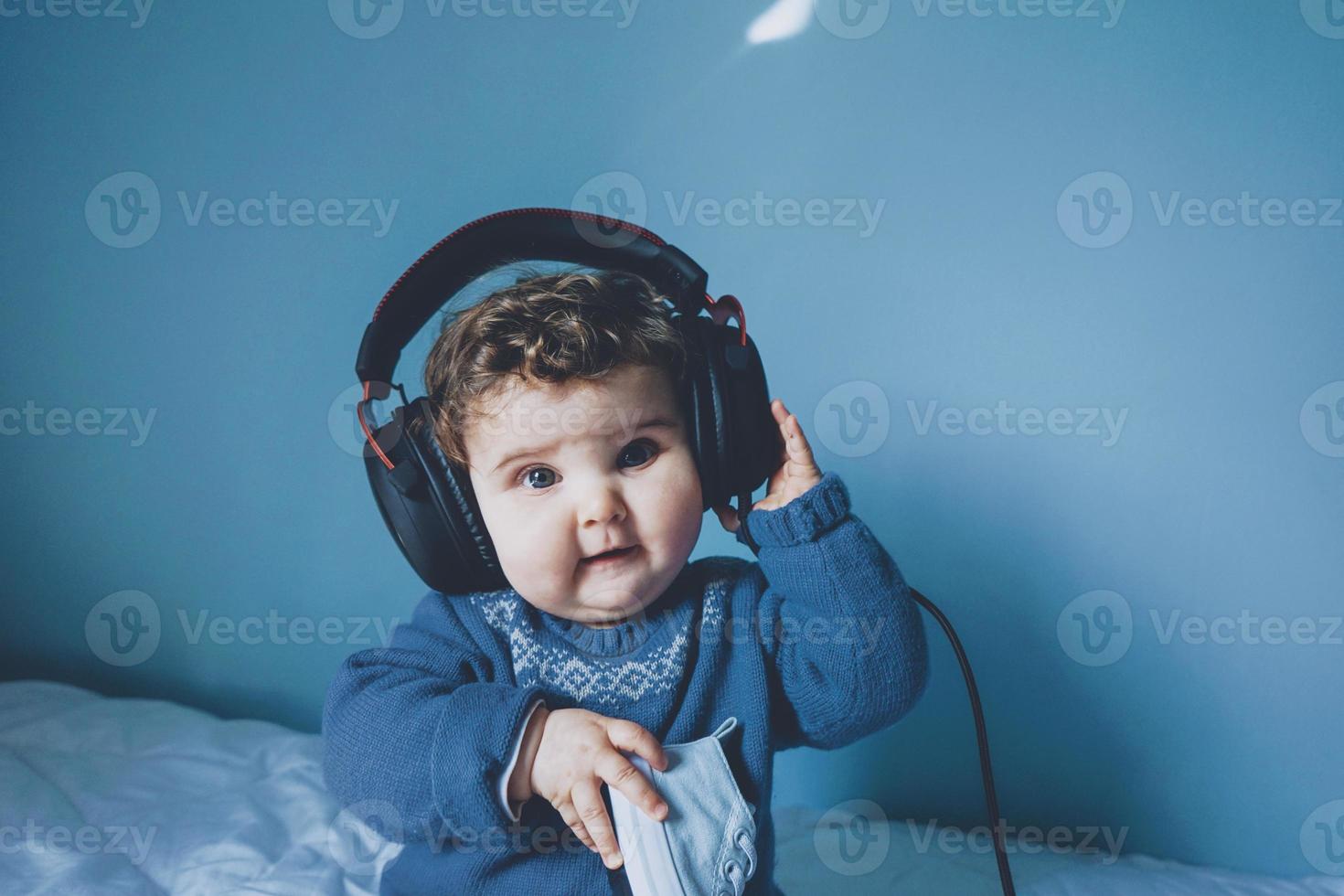 piccolo bambino che gioca con le sue cuffie di papà foto