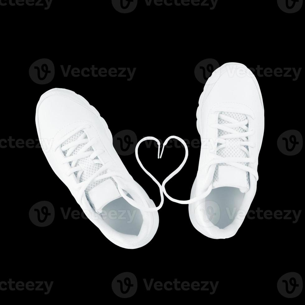 scarpe sportive bianche e forma di cuore da lacci isolati su sfondo nero foto