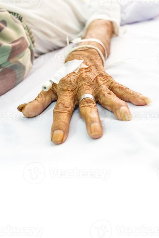 mano del paziente anziano con spina sul letto in ospedale e area vuota nella parte inferiore foto