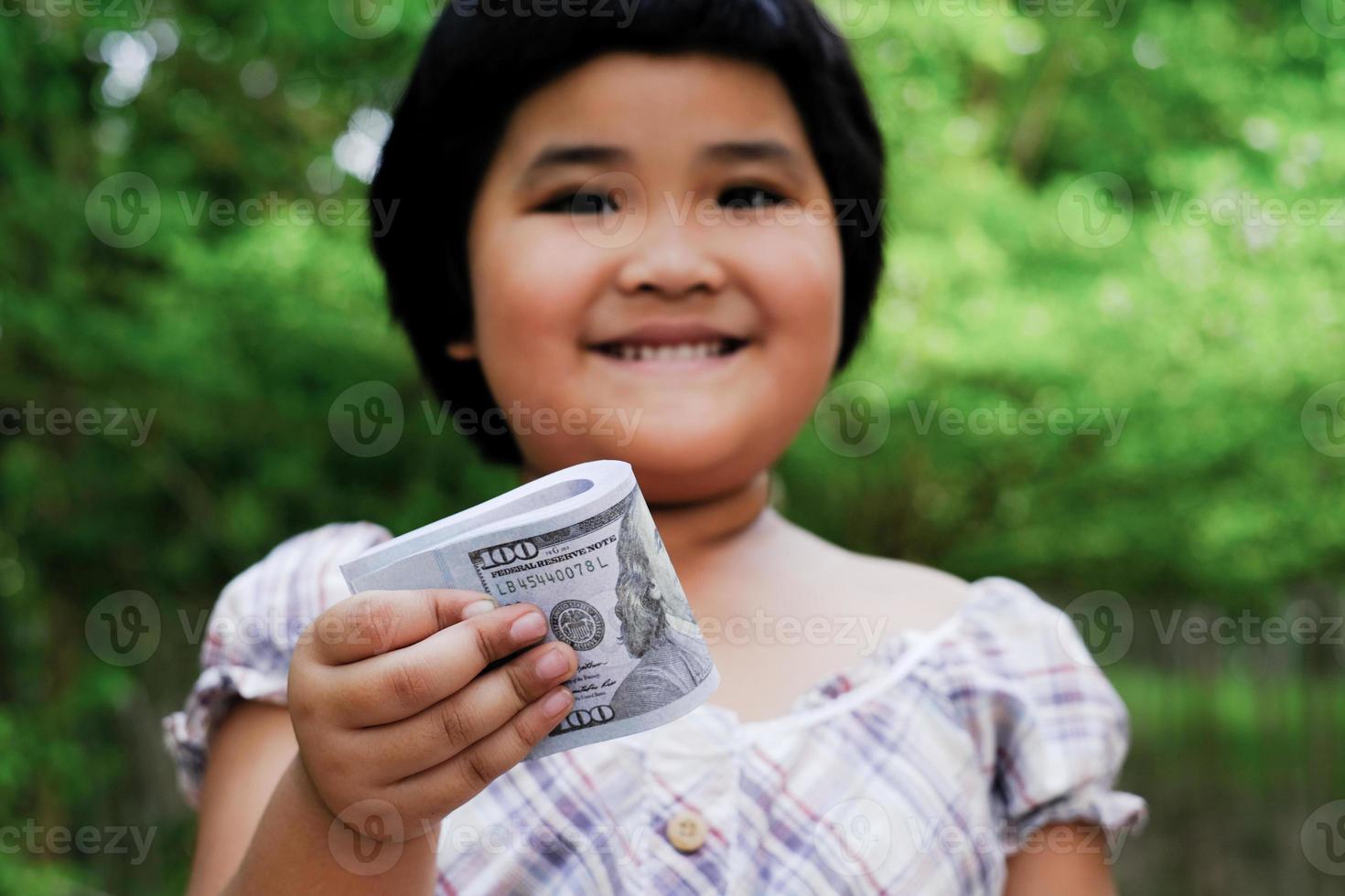 Asia ragazza mano che tiene i soldi fasci di banconote da 100 dollari americani foto