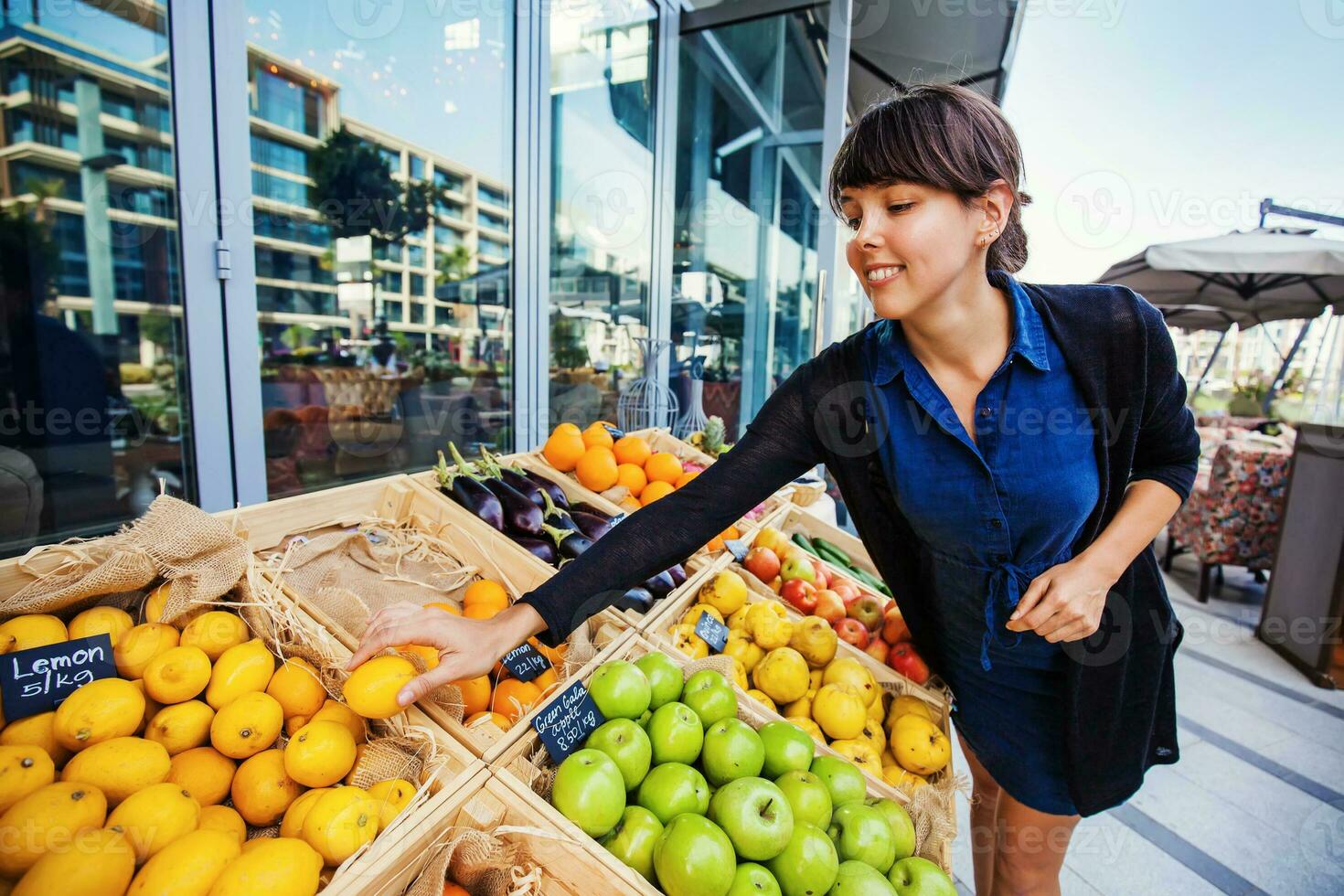 giovane caucasico donna raccolta limoni a partire dal un Aperto mercato negozio foto