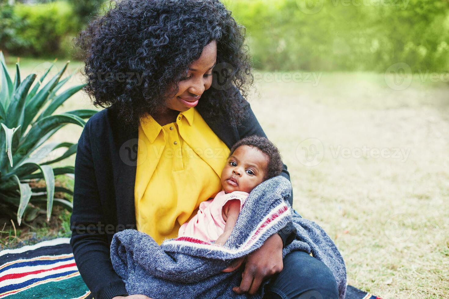 africano donna Tenere sua bambino avvolto nel coperta nel il parco foto