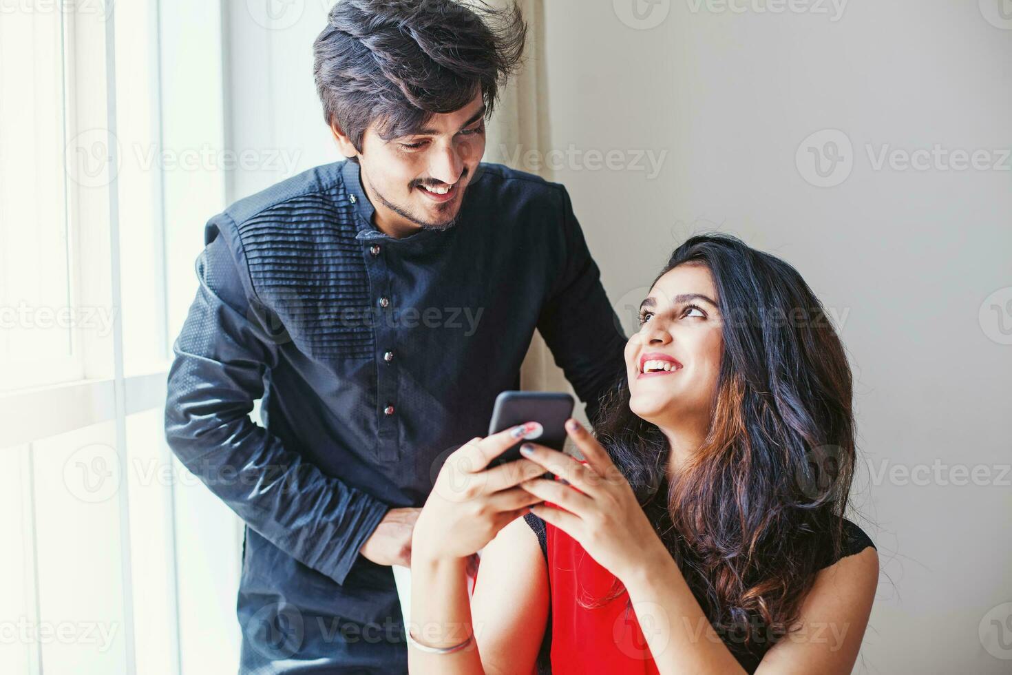 indiano uomo e donna utilizzando mobile Telefono insieme e sorridente felicemente foto