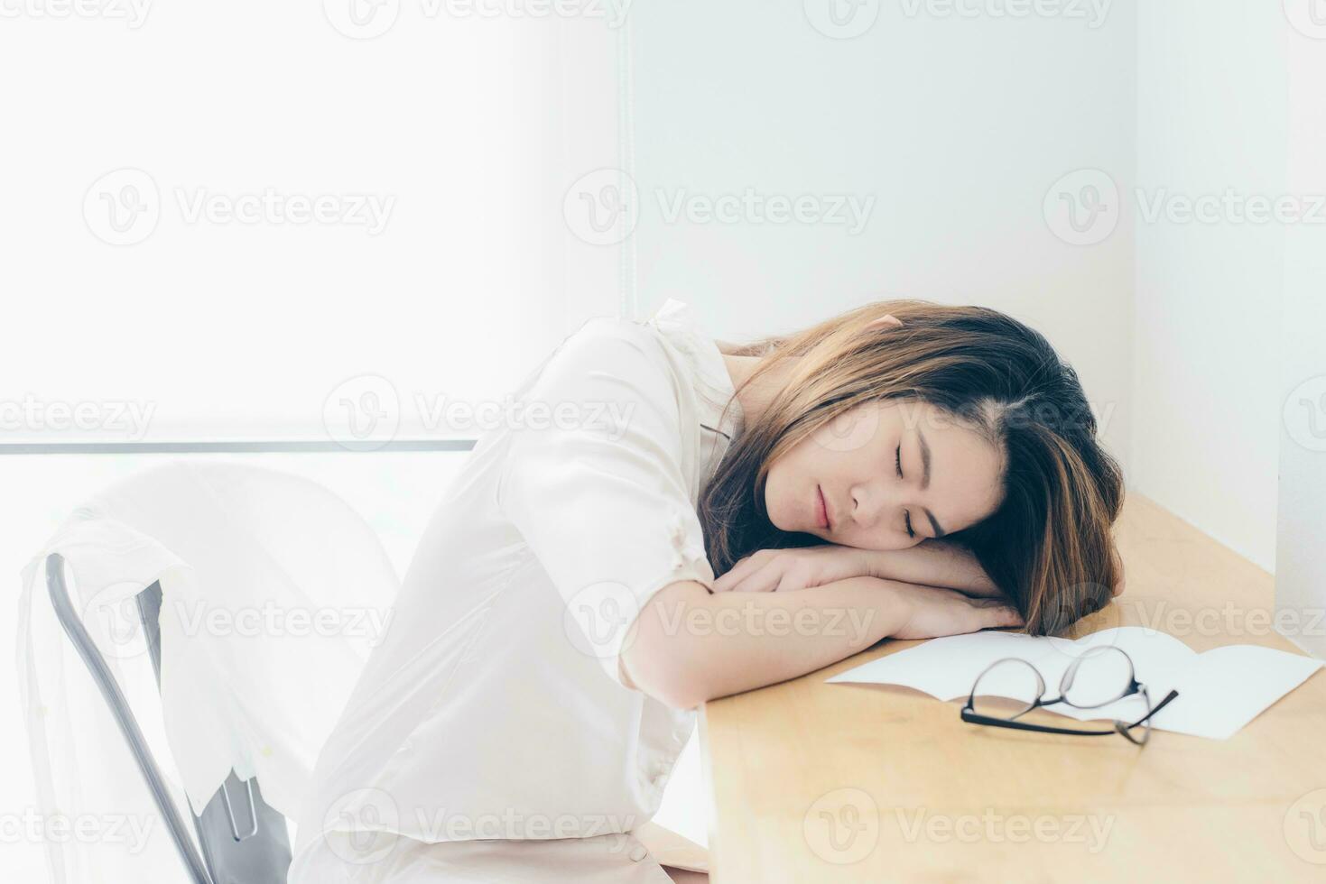 ritratto di asiatico donna addormentato su il scrivania dopo sua opera col tempo. foto