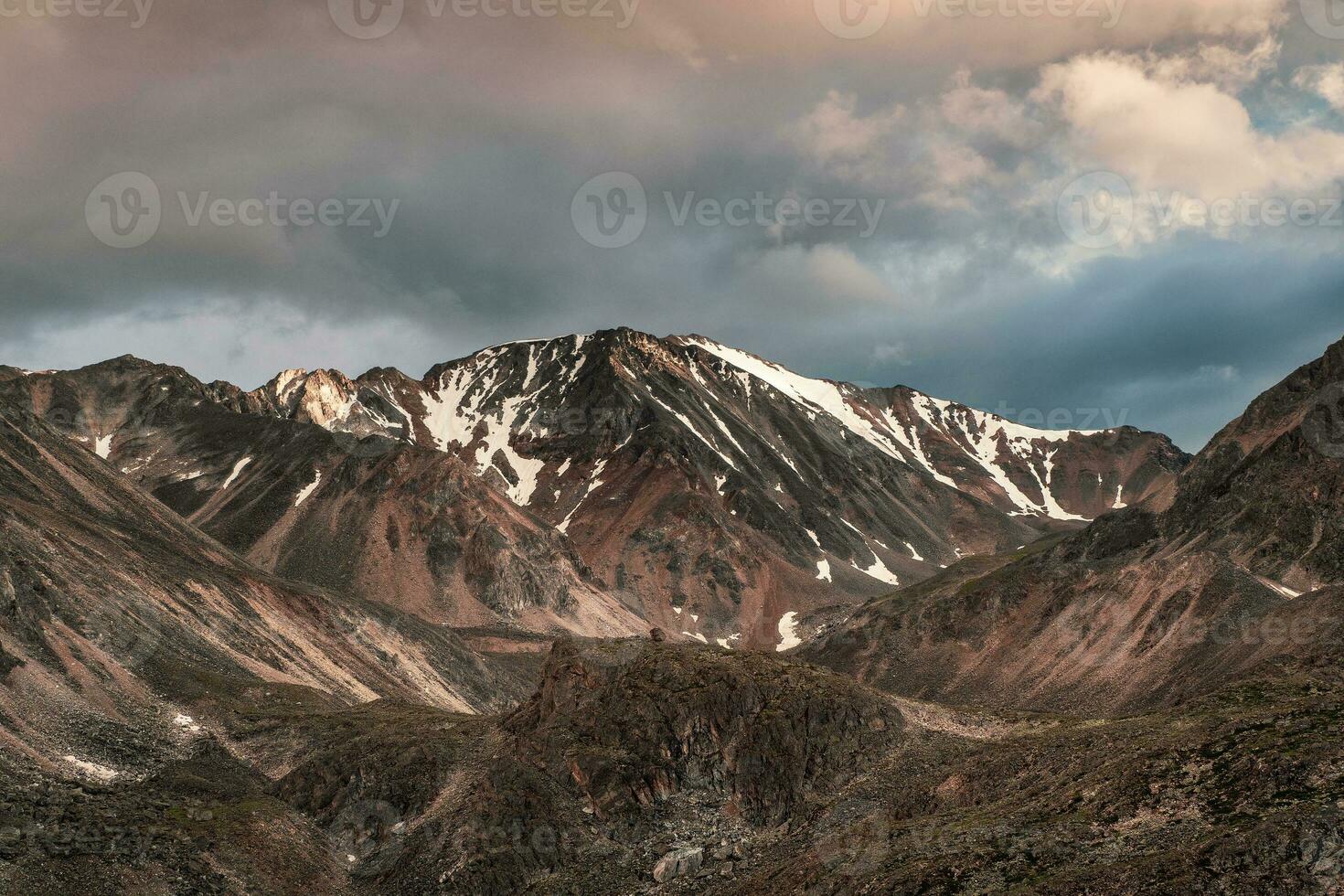 colorato paesaggio con alto nero montagna con neve e acuto rocce sotto sera nuvoloso cielo. drammatico Visualizza per grande montagna con muschioso superiore con neve a variabile tempo atmosferico. foto