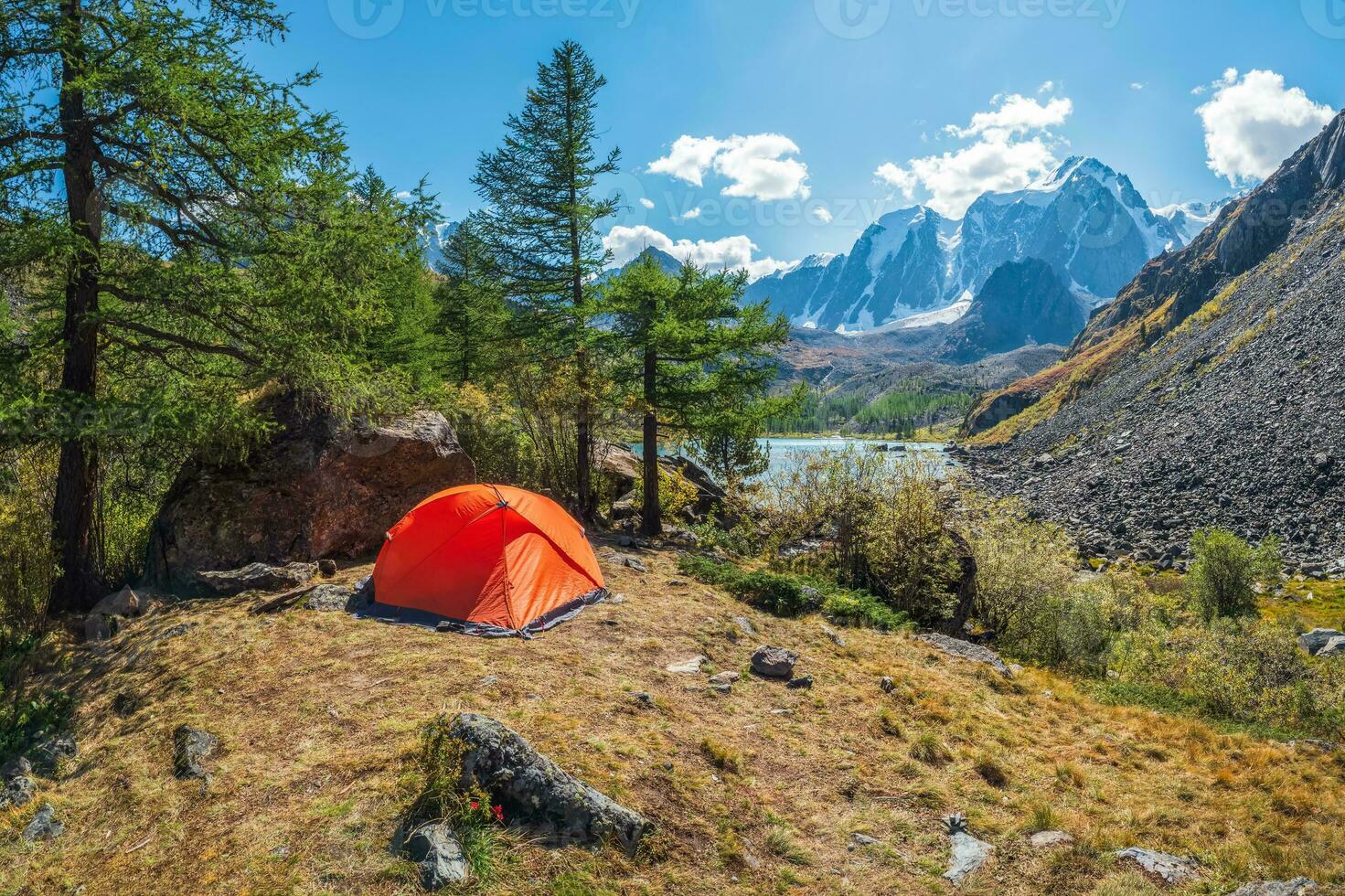 turismo concetto. solitario tenda nel il montagna foresta. arancia campeggio tenda su il riva nel il luce del sole. foto