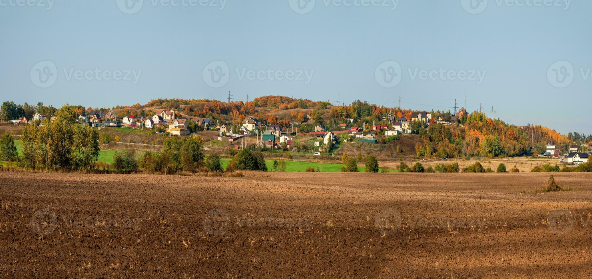 un' largo panorama di il collettivo azienda agricola campo nel davanti di il villaggio su un' verde collina. foto